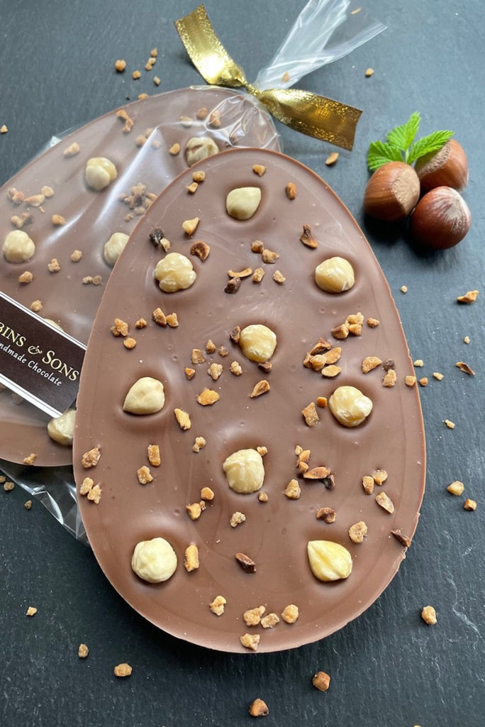 Milk chocolate easter egg with whole and chopped and caramelized hazelnuts