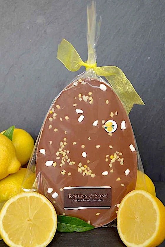 Sicilian Lemon Crunch Easter Egg. Oval shaped milk chocolate bar flavoured with lemon, topped with meringue in clear packaging tied with a yellow ribbon bow