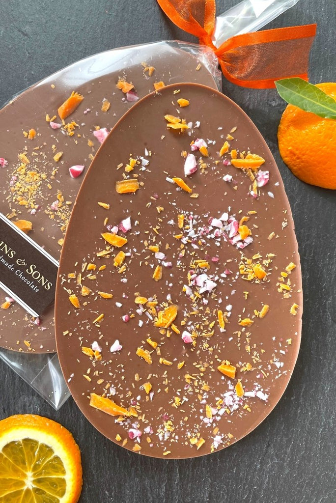 Orange milk chocolate easter egg. Oval shaped milk chocolate bar flavoured with Valencian orange oil extract and topped with belgian orange chocolate shavings and fuit candy cane.