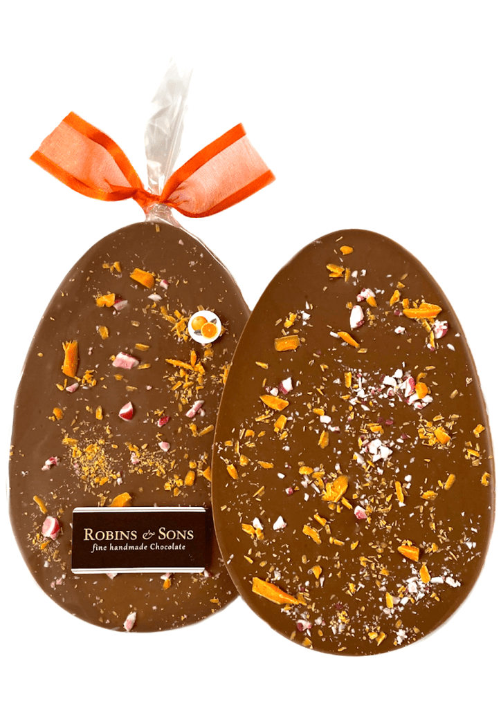 Orange Crackle Easter Egg. Egg-shaped orange chocolate bar topped with orange chocolate shavings and fruit candy cane, in clear packaging and tied with an orange bow.