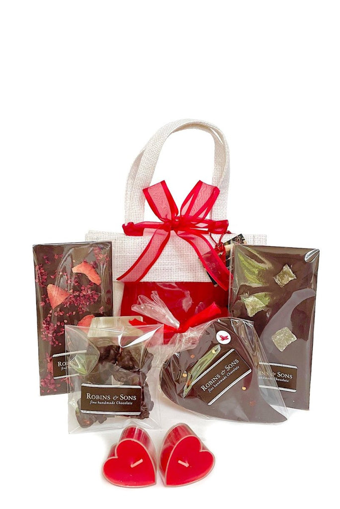 white jute gift bag containing assorted vegan suitable chocolate treats. contains 2 Slim Bars (Very Berry - vegan version, Midnight Ginger), Nut Clusters, ChiliiChoc Heart bar, 2 heart candle votives.