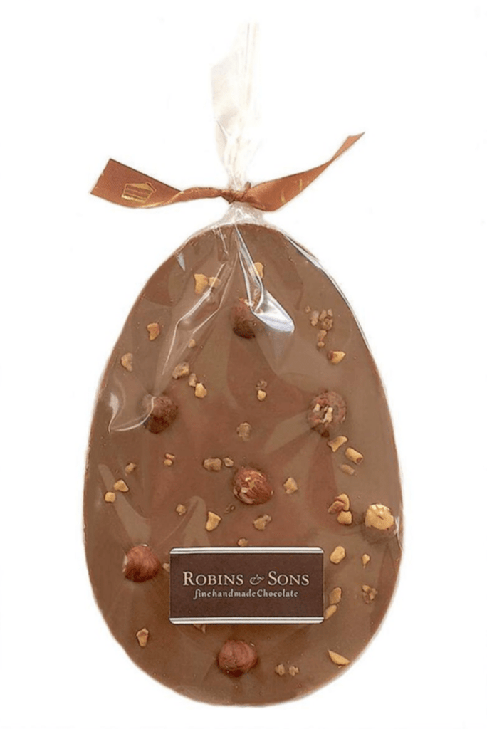 Go Nuts easter egg. Milk chocolate egg-shaped bar topped with both whole and chopped, caramelised hazelnuts in clear packaging tied with decorative ribbon bow