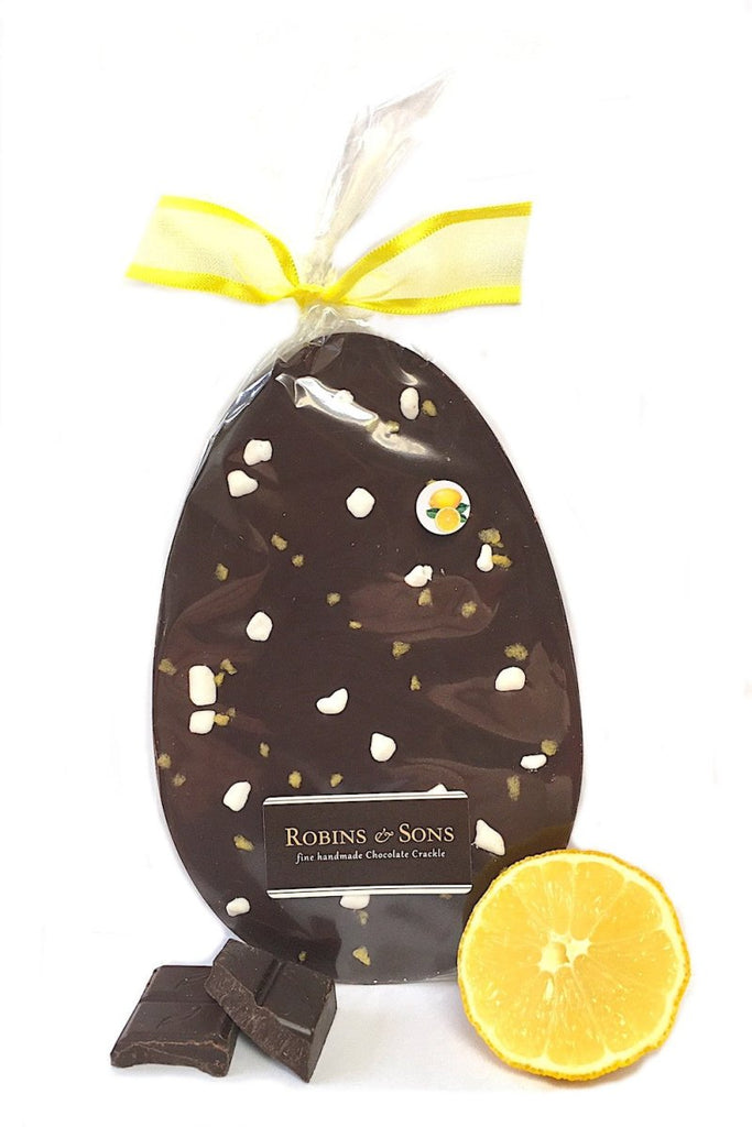 Sicilian Lemon Crunch Easter Egg. Egg-shaped dark chocolate bar topped with lemon sugar crystals and meringue, in clear packaging tied with yellow ribbon bow.