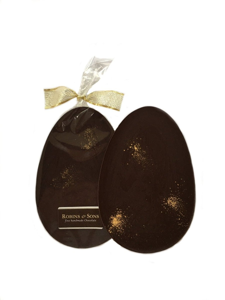 Purist Easter egg. Oval egg-shaped 80% dark chocolate egg bar with edible gold glitter, in clear packaging tied with gold ribbon.