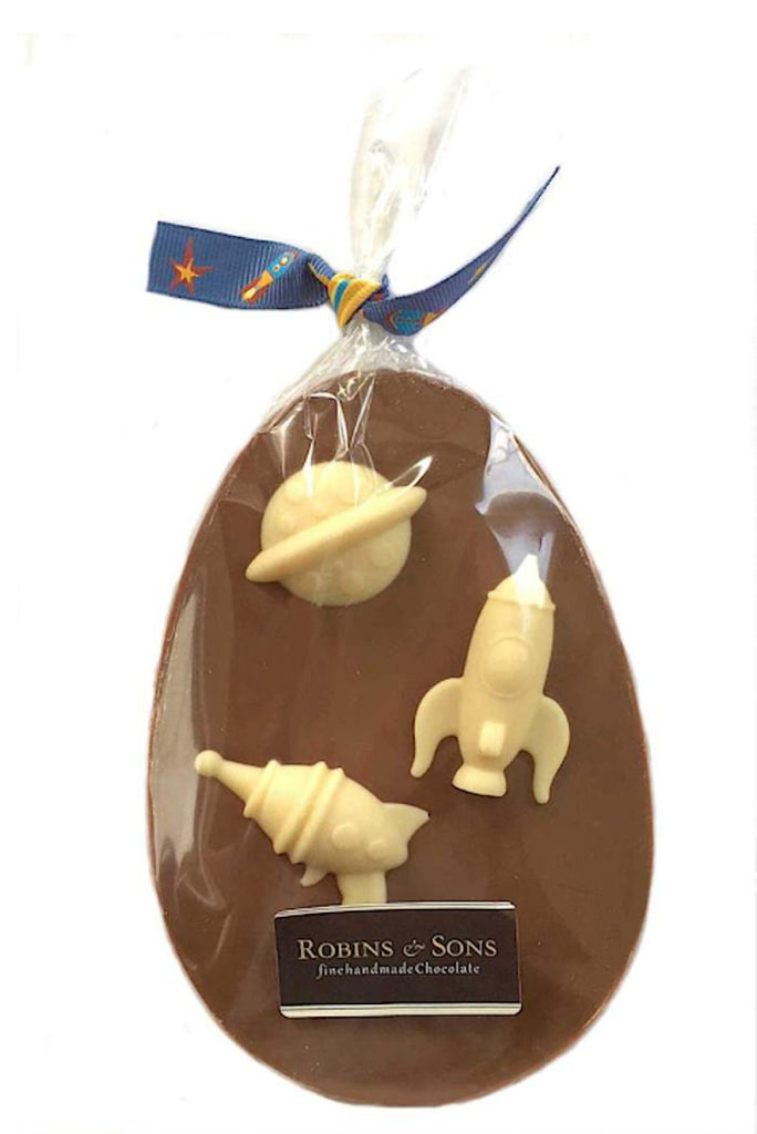 Space Explorer Easter egg. Egg shaped milk chocolate bar topped with 3 white chocolate space shapes, in clear packaging tied with space themed ribbon bow