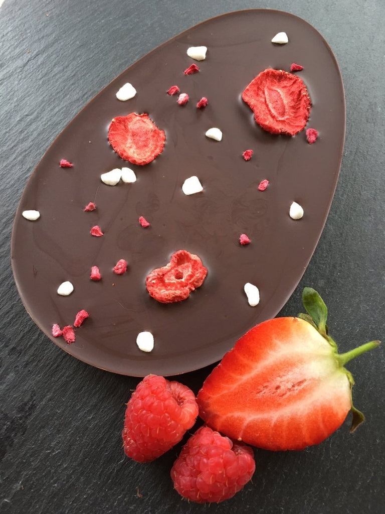 dark chocolate egg shaped bar with strawberries and raspberries, with fresh strawberries and raspberries