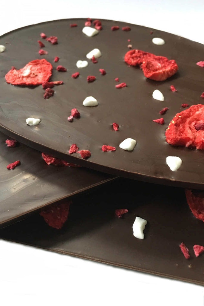 stack of dark chocolate bars topped with strawberries, raspberries and meringue