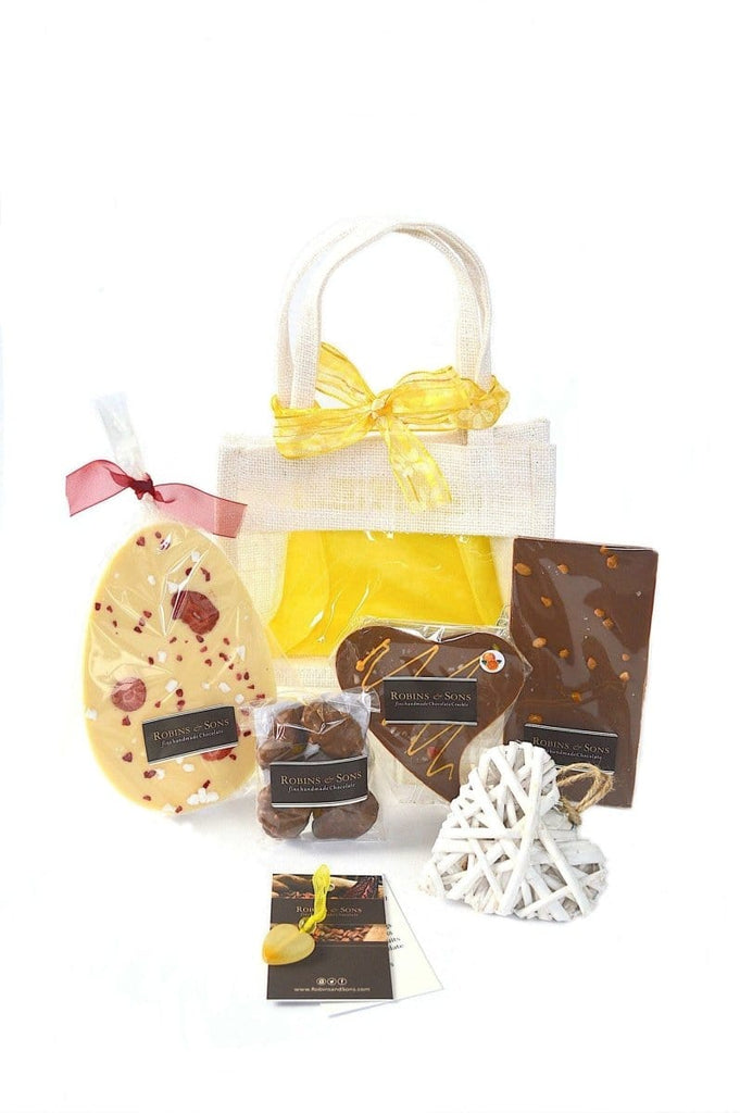 Easter chocolate gift bag containing white chocolate Easter egg with strawberries, nut clusters, orange chocolate heart, salted caramel chocolate bar, heart shaped  coaster